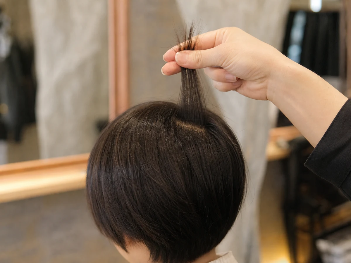 毛束を持ち上げて長さを確かめている手元