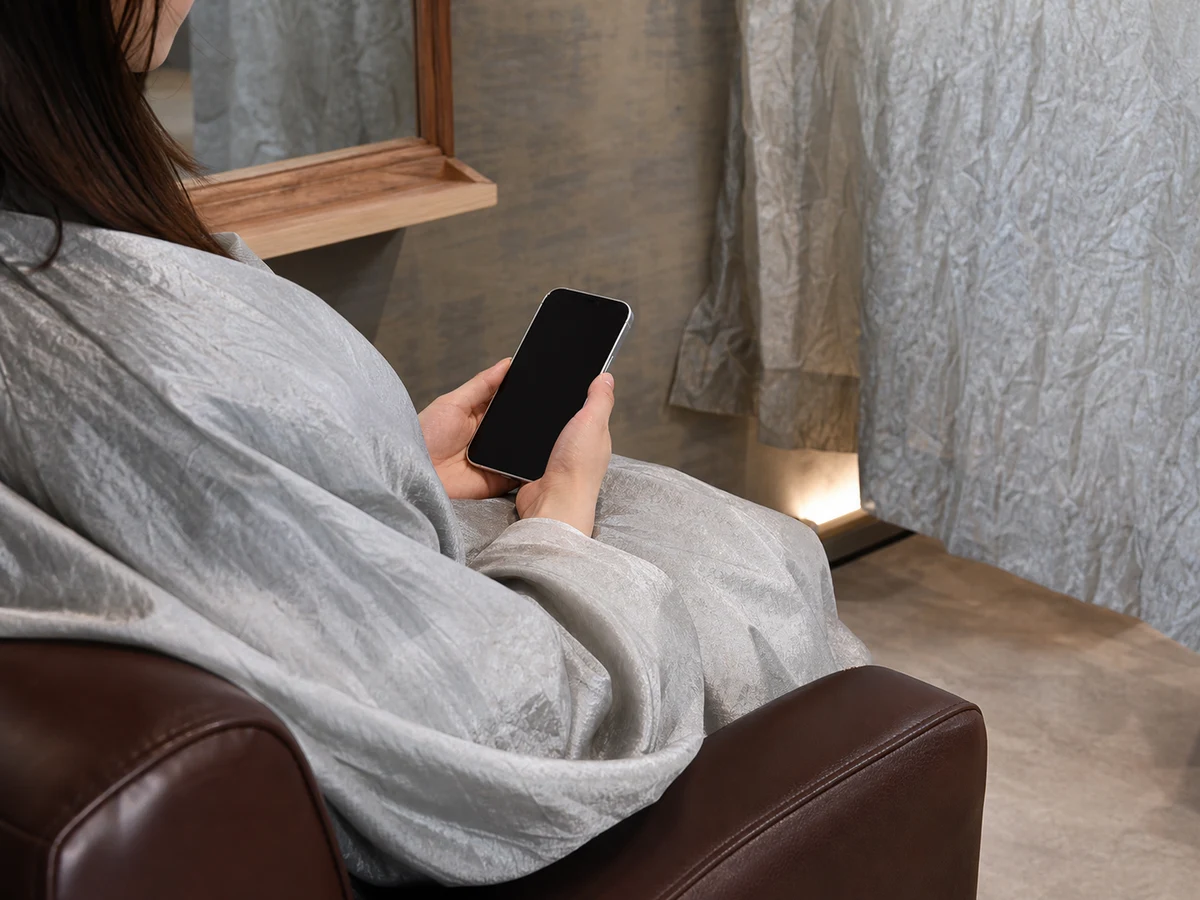施術中にスマートフォンを手に持ってくつろぐ様子