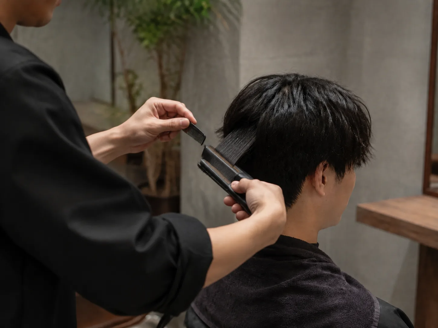 男性の髪の根元にハケでカラー剤を塗っている手元